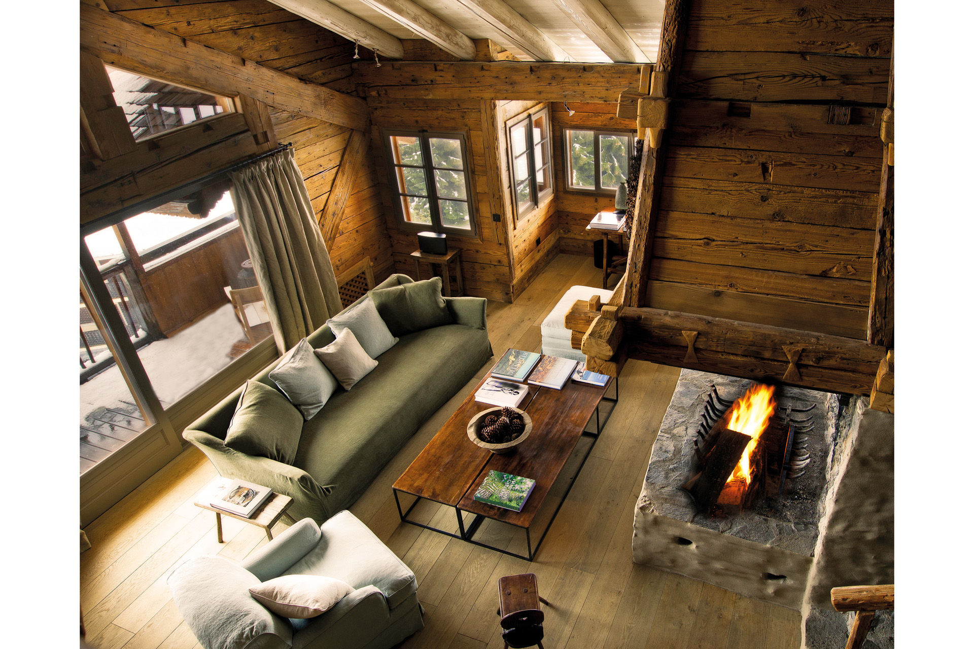 a wood panelled ski suite shot from above with coffee table, fire and sofa