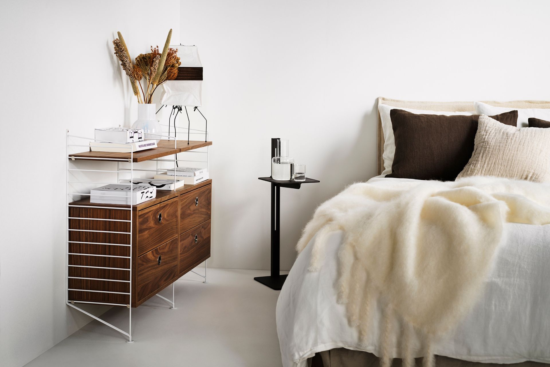 Scandi-style bedroom with white bedding, cream furs and wooden shelving