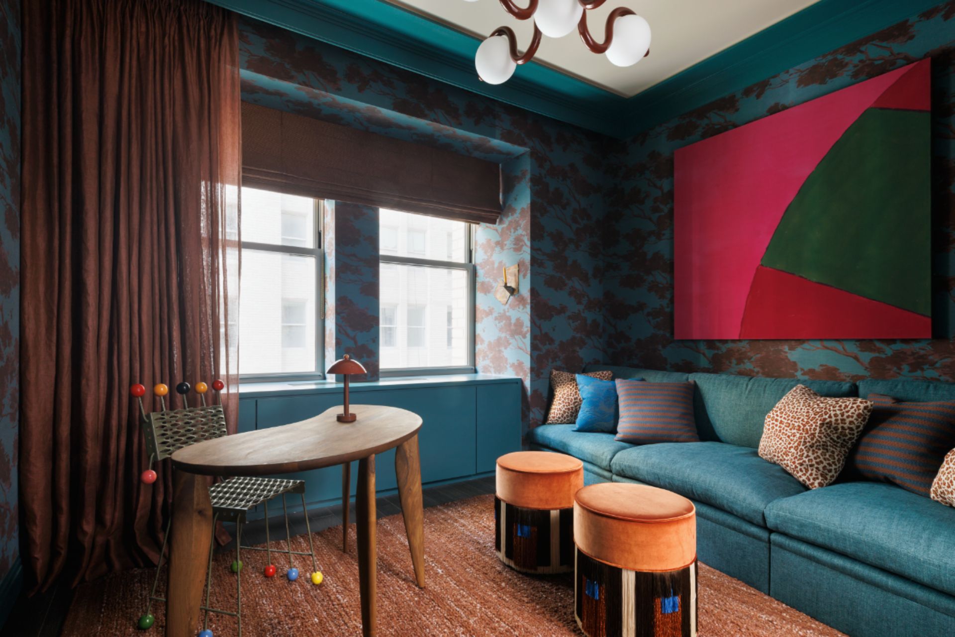 Teal snug with botanical wallpaper and orange accents.